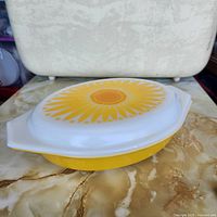 Casserole with lid on, showing yellow base and daisy lid