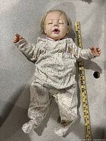 Full body view of the Hasbro Real Baby Doll lying flat, showing floral sleeper and closed eyes.