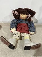 Full body front view of the 25-inch Little Souls cloth doll seated showing outfit and shoes.