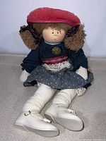 Full view of the 25-inch Little Souls cloth doll sitting upright, showing outfit and hat.