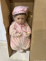 Full view of the unopened box containing the doll wrapped in plastic, showing the entire doll and outfit.