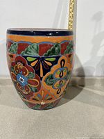 Side view of the vintage ceramic outdoor side table showing detailed floral and geometric patterns in orange, blue, green, and red.