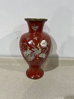 Full view of red cloisonne vase with mother of pearl inlay and brass rim.