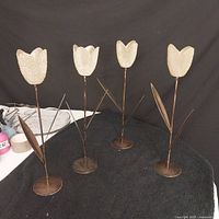 Set of 4 tulip-shaped candle holders with gold frost glass petals and brass-colored metal stems and leaves on black background.