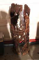 Three-piece wooden elephant carving standing about 3 feet tall with glazed details and interstitial carving detail. The carving appears broken and separated into three parts, showing various elephant figures.