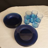 Blue vintage glass dish set with 8 dinner plates, 8 pasta plates, and 6 octagonal drinking glasses, arranged on fabric surface.