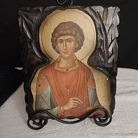 Front view of carved wooden plaque featuring a painted Byzantine icon of a saint