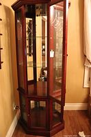 Front angle view of the wooden display cabinet with two etched glass doors, showing the upper and lower compartments with glass shelves inside and ornate etched designs.