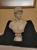 Front view showing full bust on pedestal against backdrop