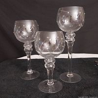 Three clear glass candle holders of varying heights arranged together, showing full shapes and size difference.