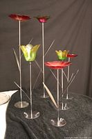Set of five garden decorations in glass flowers with silver metal stems and leaves shown from front angle on black cloth background