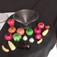 Photo of 12-inch jumbo martini glass with 17 assorted vintage decorative glass fruits and vegetables including tomatoes, apples, garlic, corn, eggplant, and bananas on black cloth background.