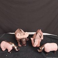Four animal figurines set on black fabric background, showing two large terra cotta pieces with bronze glaze and two small bronze rhinos.
