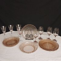 Photo of full set laid out on white cloth with black background showing plates and various wine glasses.
