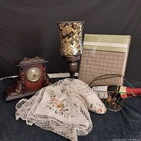 Photo showing all items together including clock, hurricane candle holder, copper wire wine basket, and tablecloth in package.