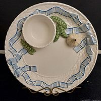Top view of vintage Bella Casa ceramic platter with attached dip bowl featuring 3D garlic bulb and pea pod decorations, and blue ribbon detailing.