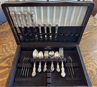 Open fitted case showing upper lid with silver-plated knives and lower tray with forks and spoons arranged in individual slots