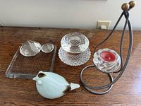 Clear glass square tray with two faceted crystal pieces and white bird figurine on wood surface