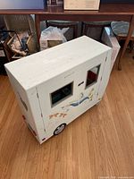 White American Girl camper with windows and decorative decals on hardwood floor.