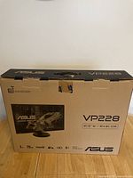 Box of ASUS VP228 gaming monitor, showing model VP228 and screen size 21.5 inches / 54.61 cm, highlighting gaming features such as 1ms response time and 75Hz refresh rate.