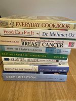 Stack of 10 health and nutrition cookbooks and guides with titles visible, including Food Can Fix It, Medical Medium, Quantum Healing.