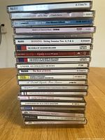 Stack of classical music CDs in jewel cases showing titles such as Naxos, Rossini String Sonatas, The World of Vaughan Williams, and operatic collections.