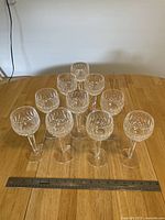 Ten stemware glasses arranged in pyramid formation on table with ruler in foreground