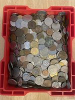 Top view of red hard plastic box filled with assorted coins