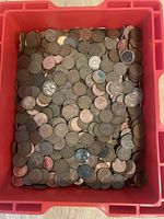 Top-down view of red plastic box filled with assorted pennies