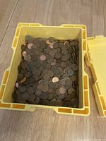 Yellow hard plastic box open, showing loose pennies inside