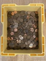 Overhead view of yellow plastic bin filled with pennies