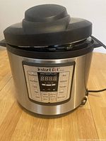 Front view of the Instant Pot IP-LUX60 V3 electric pressure cooker showing the digital control panel and black lid with handle.