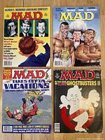 Four MAD Magazine issues laid out showing front covers with colorful parodies and satire.