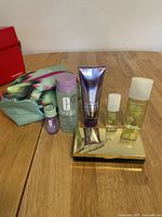 Photo of Clinique skincare items including facial soap, cleansing mousse, and makeup remover, alongside Elizabeth Arden Green Tea Honeysuckle perfume sprays, Lancome limited edition eye and face palette, and a Clinique pouch.