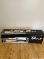 Boxed stainless steel fish poacher shown in original packaging with product images and labeling visible.