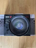 Front view of a collectible tin camera-shaped container with a 550-piece puzzle label and classic camera lens image on the packaging.