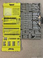 Top view of yellow case with drill bits and screwdriver bits neatly organized, alongside gray case with socket wrenches and ratchet tools.