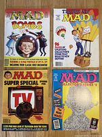 Four MAD Magazine issues displayed with front covers visible showing different themes and caricatures.