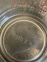 Close-up photo of the bottom of a Pyrex clear glass measuring cup with embossed markings and brand logo.