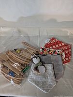 Wooden train tracks in plastic bag and baby bibs with crocheted owl ring beneath plastic