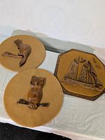 Overall view of three wooden mid-century modern wall plaques on light surface