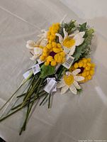 Full bunch of assorted crochet flowers with metal stems laid together showing various flower types and attached green crocheted leaves.