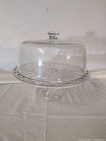 Glass cake tray with transparent dome lid placed on top, showcasing the full assembled item.