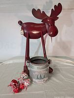 Full view of red metal moose with attached galvanized metal container holding Christmas ornaments.