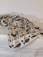 Wide view of the fabric laid out showing the block print pattern with birds, plants, and abstract shapes.