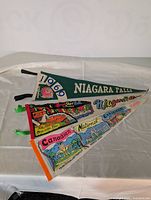 Three vintage Canadian pennants laid flat on a white surface showing the designs and text clearly.