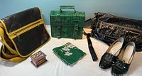 Three purses on a white surface: mustard canvas and brown leather satchel, emerald green briefcase style purse, and shiny black leather bag; small hand-painted wooden box, vintage embroidered handkerchief, and black vintage heels size 7.5