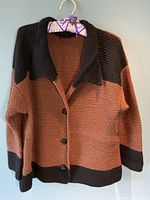 Brown and black knit button-up sweater with a collar, hanging on hanger
