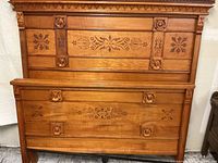 Headboard and footboard leaning against wall showing full front view of carved panels