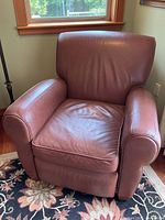 Front and side view of the brown recliner showing armrests, cushioned seat, and back support